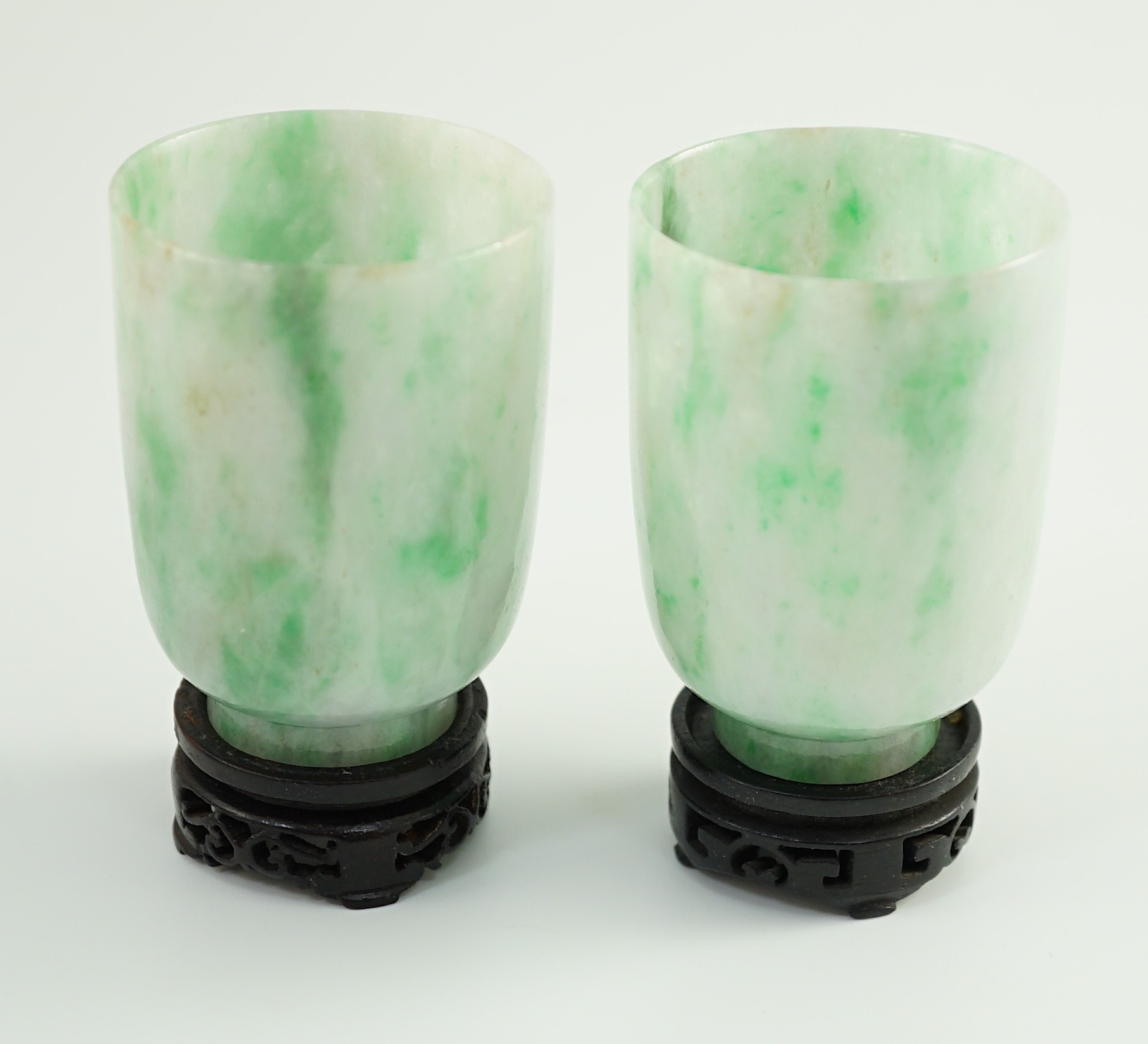 A pair of Chinese jadeite cups, 6.2cm high, wood stands, fitted box